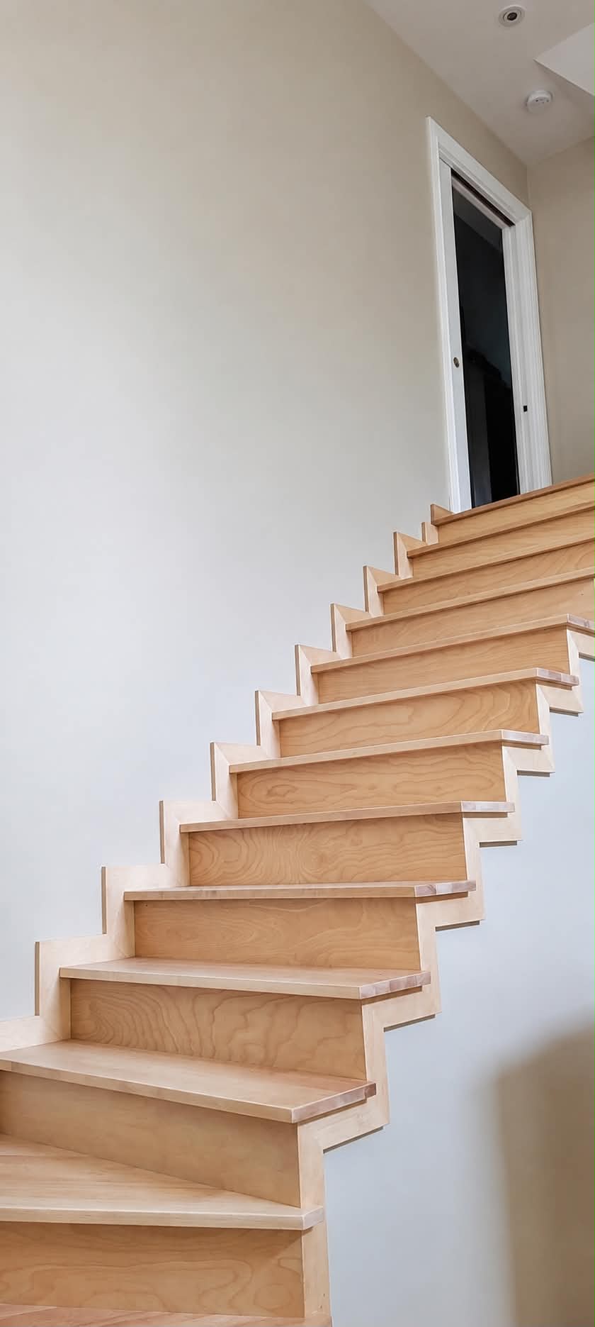 Escalier en bois naturel entouré de murs fraîchement peints